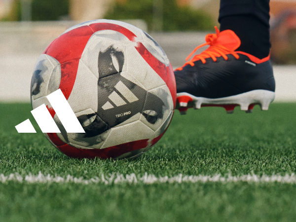 Soccer cleat kicking a soccer ball on turf.